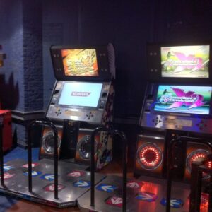 Two North American Dance Dance Revolution X series arcade cabinets with dance stages in an arcade