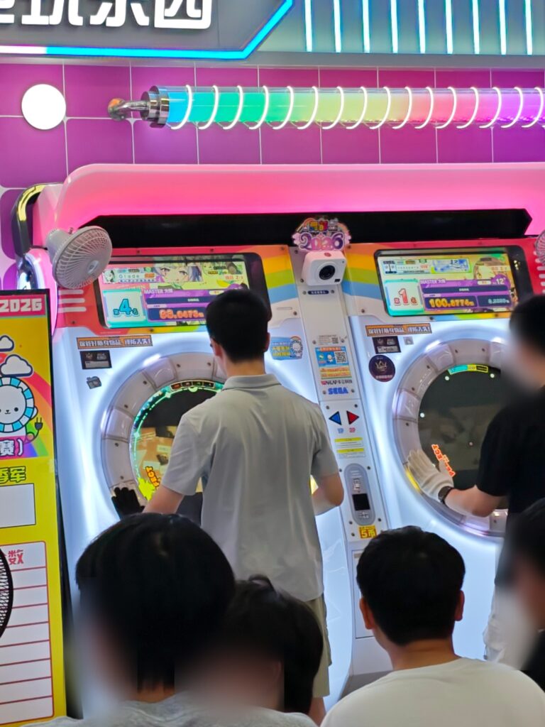 Two maimai DX arcade cabinets in an arcade in China, with players at the touch rings