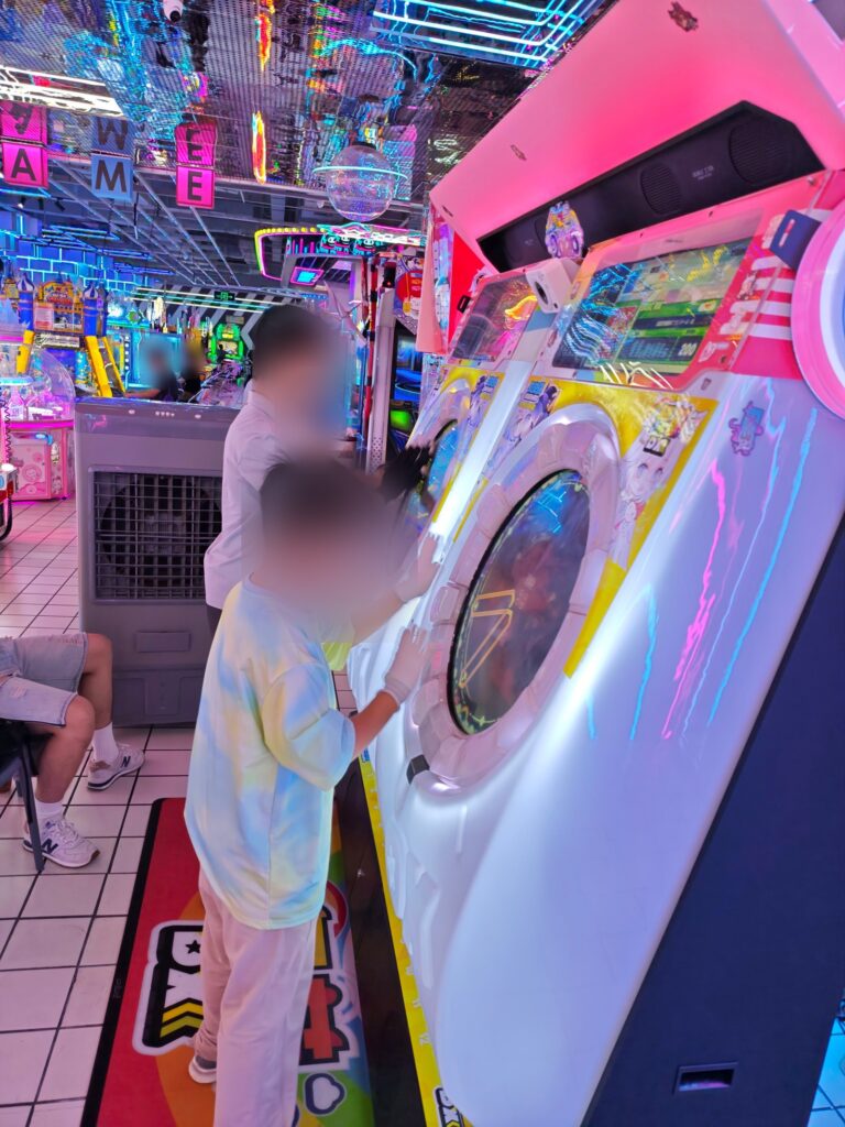 A maimai DX arcade cabinet in China, side view, with players using the touch ring
